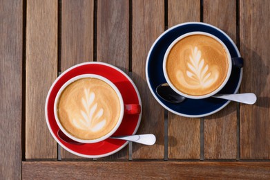 Cups of aromatic coffee on wooden table, flat lay