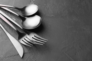 Photo of Beautiful cutlery set on black table, closeup. Space for text