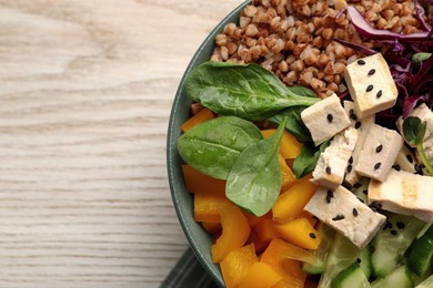 Delicious vegan bowl with bell pepper, tofu and buckwheat on white wooden table, top view. Space for text