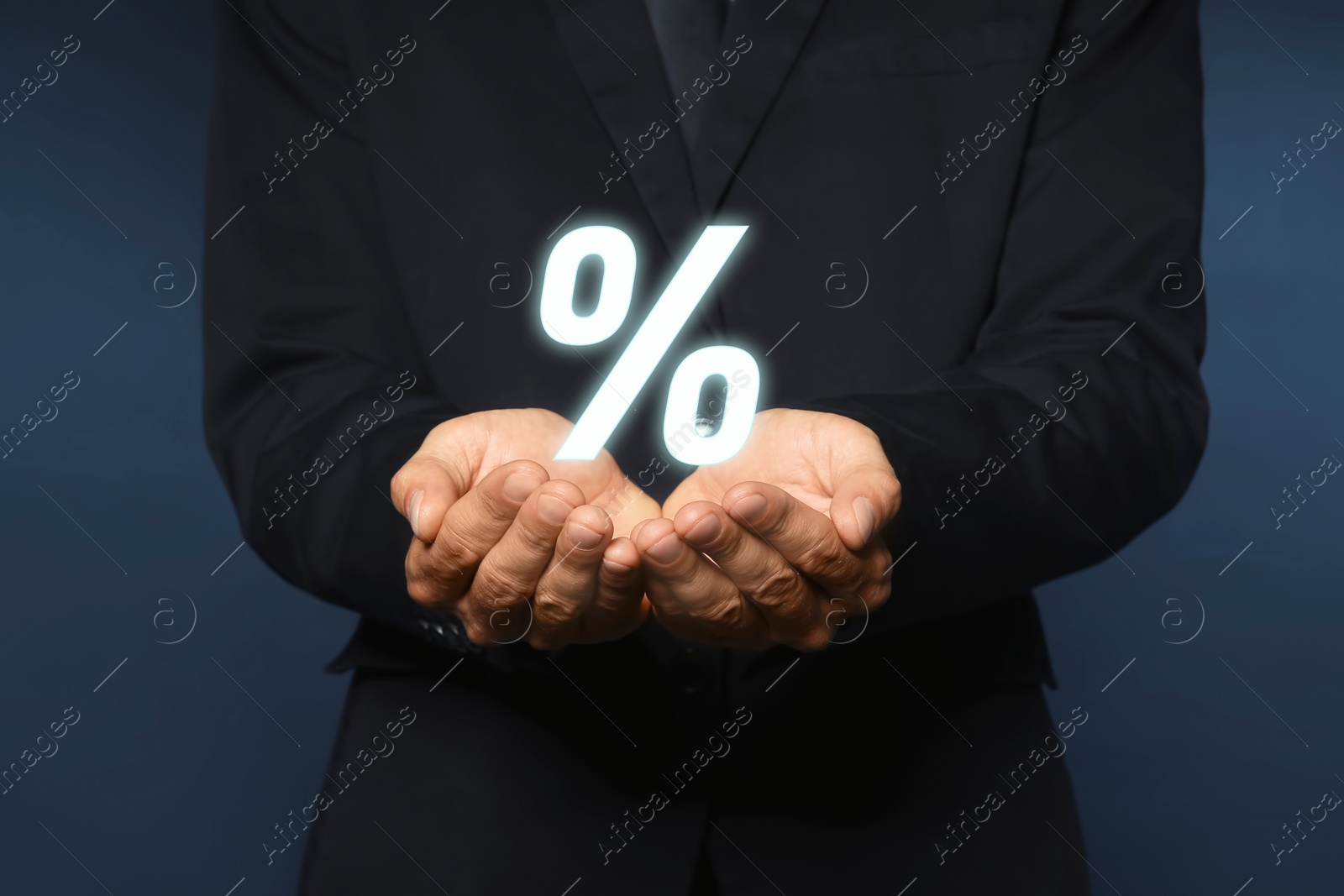 Image of Mortgage. Man holding percent sign on dark blue background, closeup