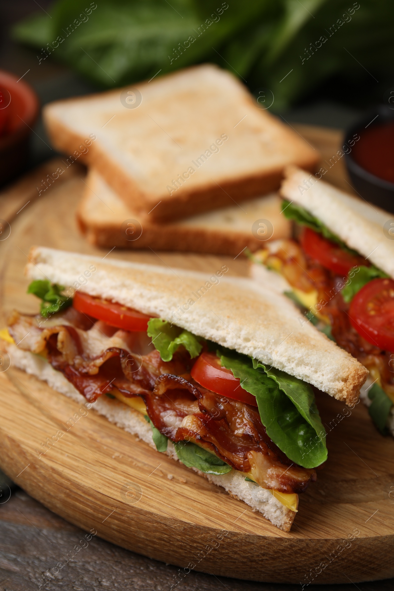 Photo of Delicious sandwiches with fried bacon on wooden table, closeup