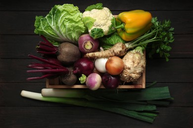 Photo of Crate full of different vegetables on black wooden table, top view. Farmer harvesting