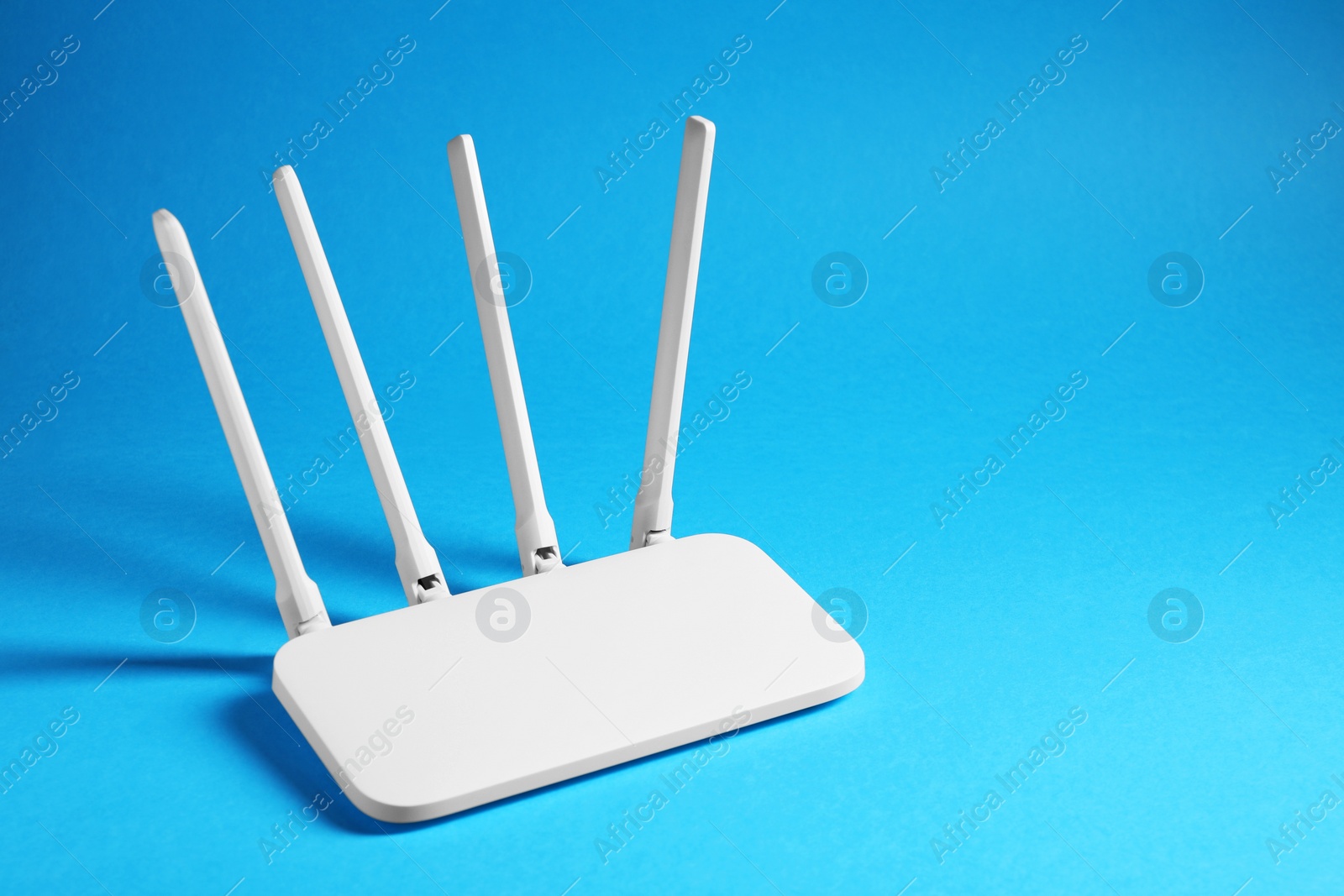 Photo of New white Wi-Fi router on blue background, space for text