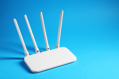 Photo of New white Wi-Fi router on blue background, space for text