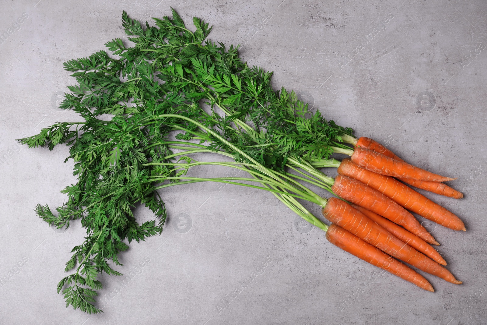 Photo of Bunch of fresh carrots on stone background, top view