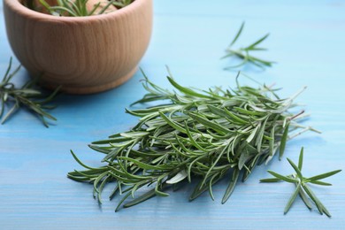 Photo of Sprigs of fresh rosemary on light blue wooden table