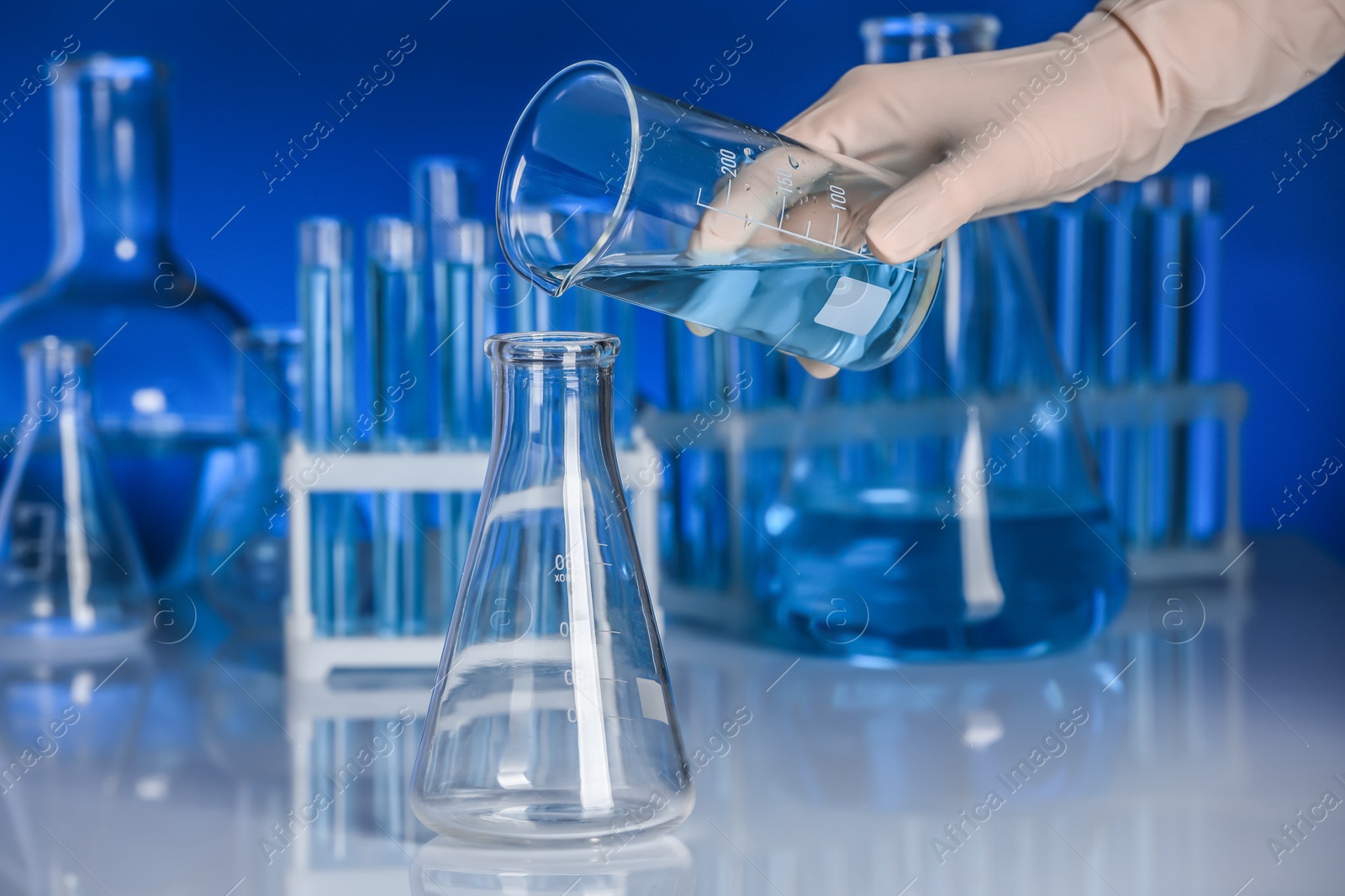 Photo of Scientist pouring liquid into flask on table. Laboratory analysis