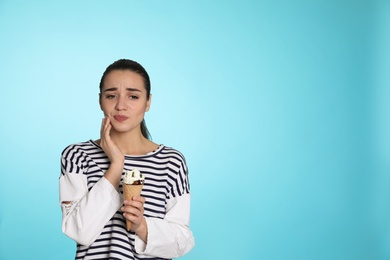 Emotional young woman with sensitive teeth and ice cream on color background. Space for text