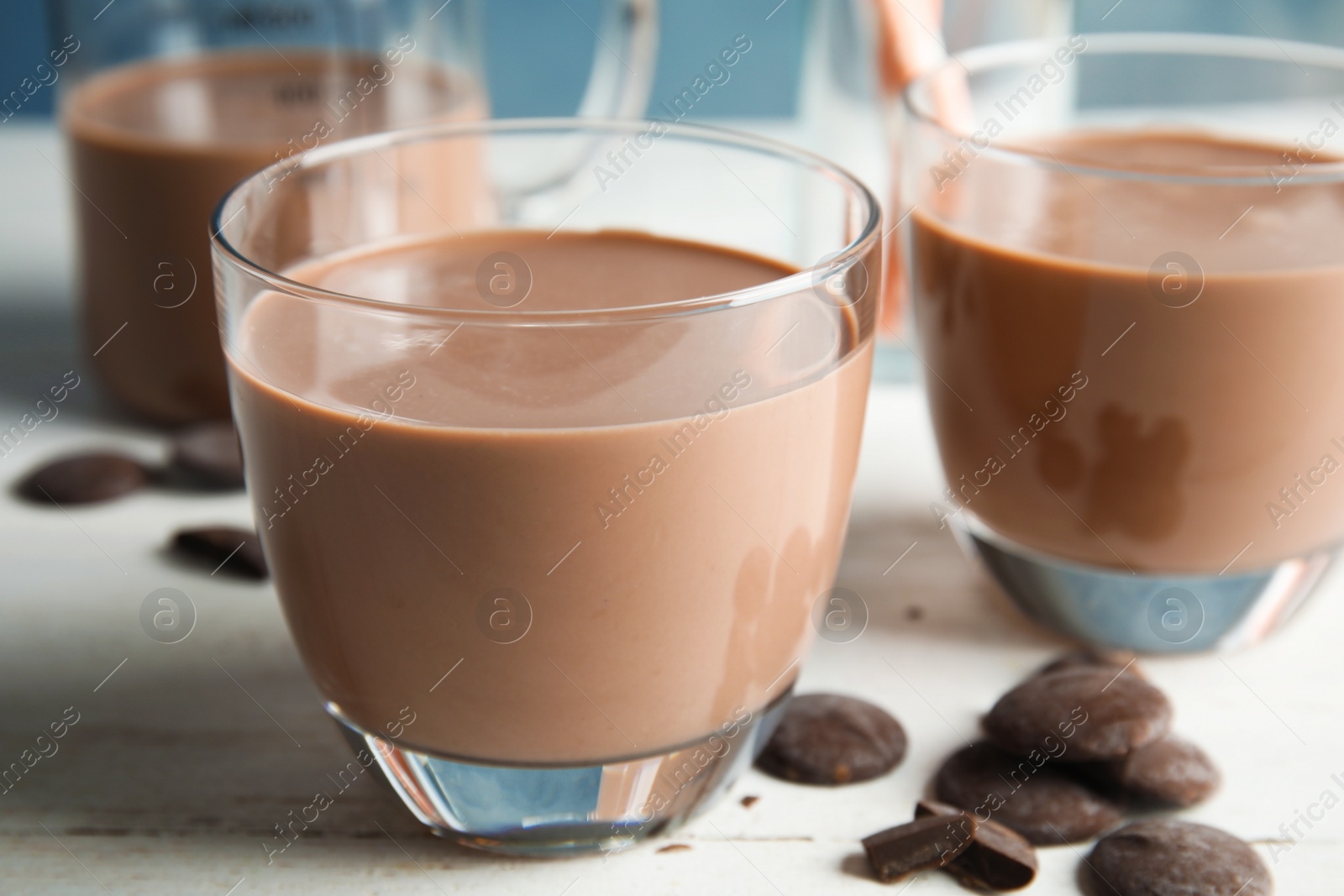Photo of Glasses of tasty chocolate milk on wooden table, closeup. Dairy drink