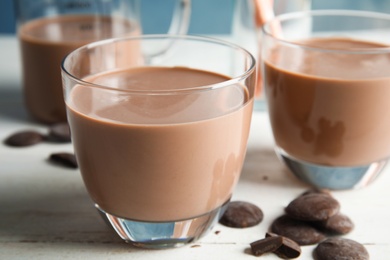 Photo of Glasses of tasty chocolate milk on wooden table, closeup. Dairy drink