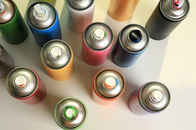 Photo of Cans of different graffiti spray paints on white table, above view