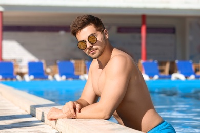 Photo of Handsome young man at swimming pool edge on sunny day