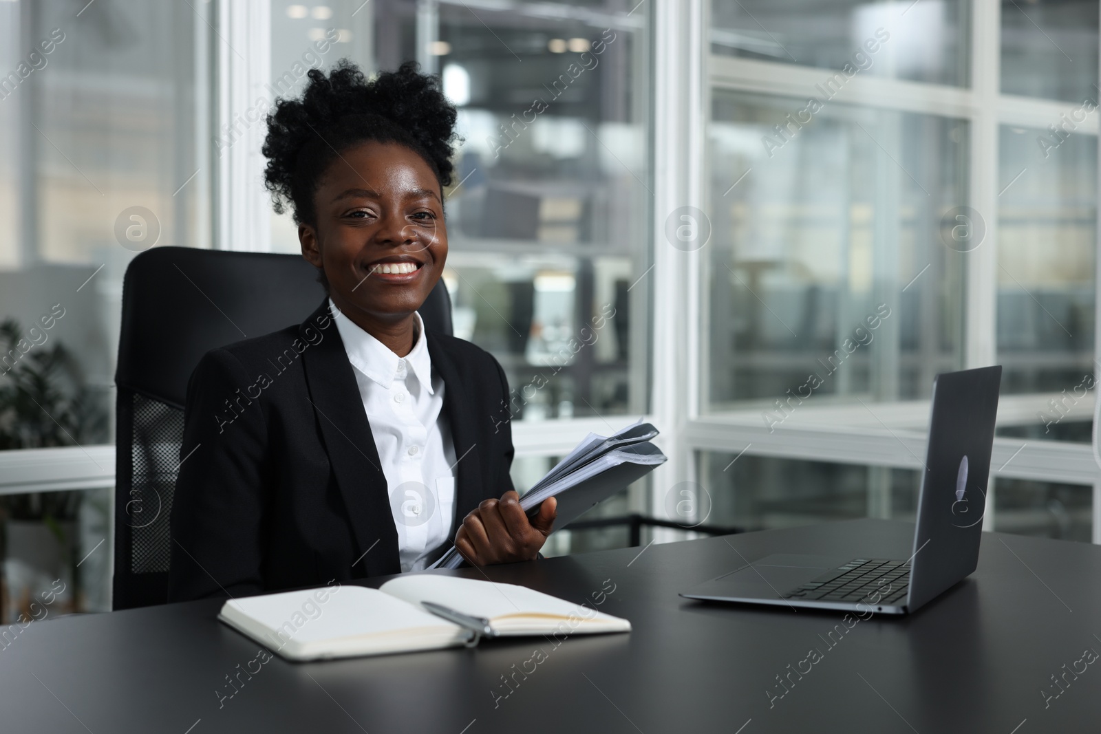 Photo of Happy woman with folders working at table in office. Lawyer, businesswoman, accountant or manager