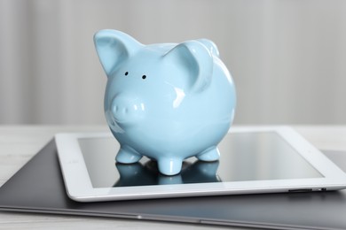 Photo of Piggy bank, tablet and laptop on white table indoors