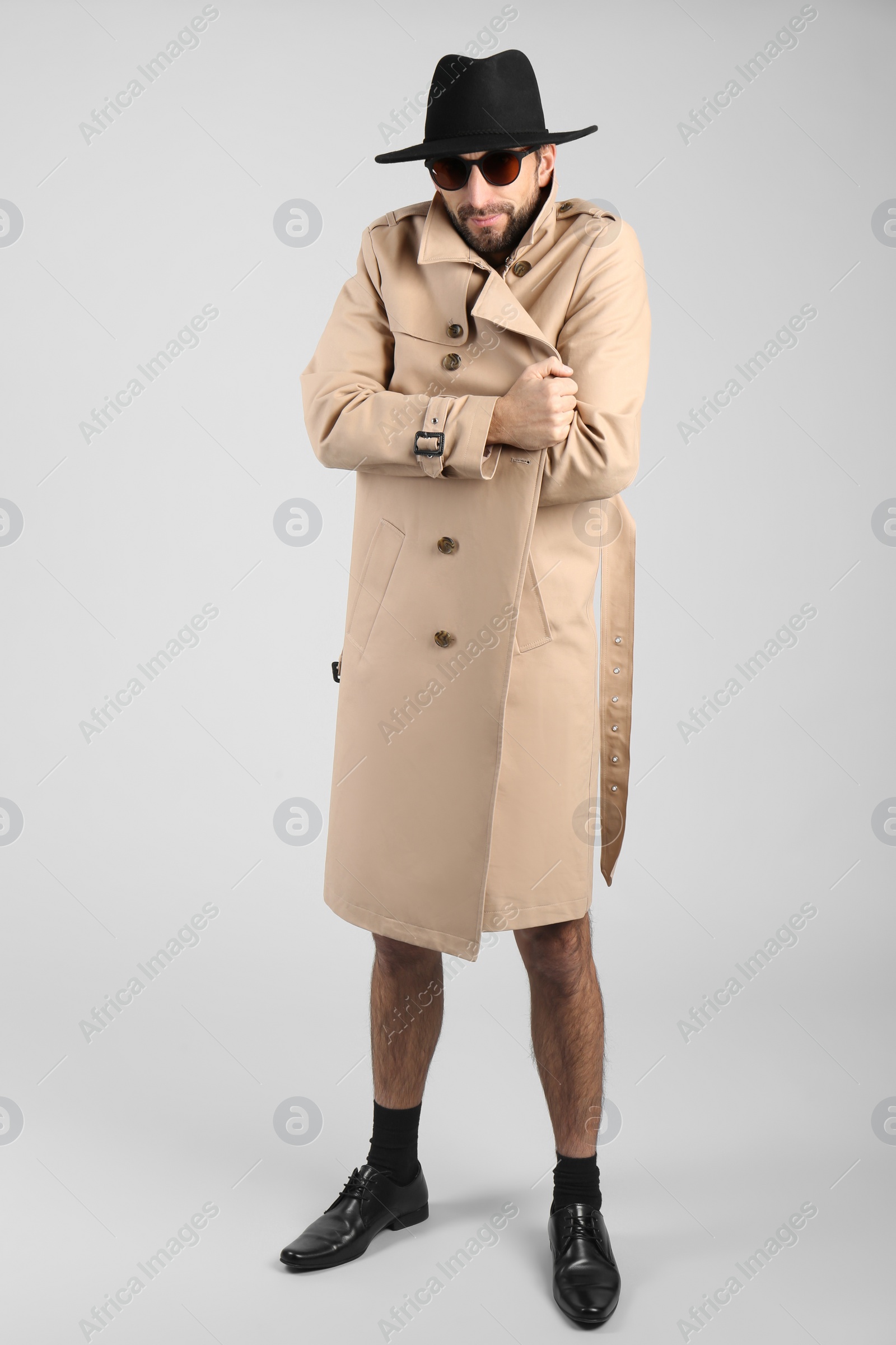 Photo of Exhibitionist in coat and hat on light background