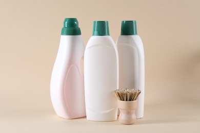 Bottles of cleaning product and brush on beige background