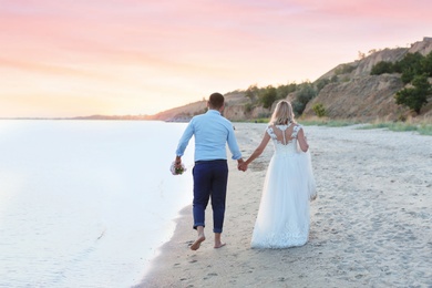 Photo of Wedding couple. Bride and groom walking on beach