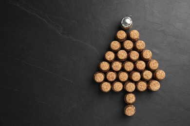 Photo of Christmas tree made of sparkling wine corks on black background, flat lay. Space for text