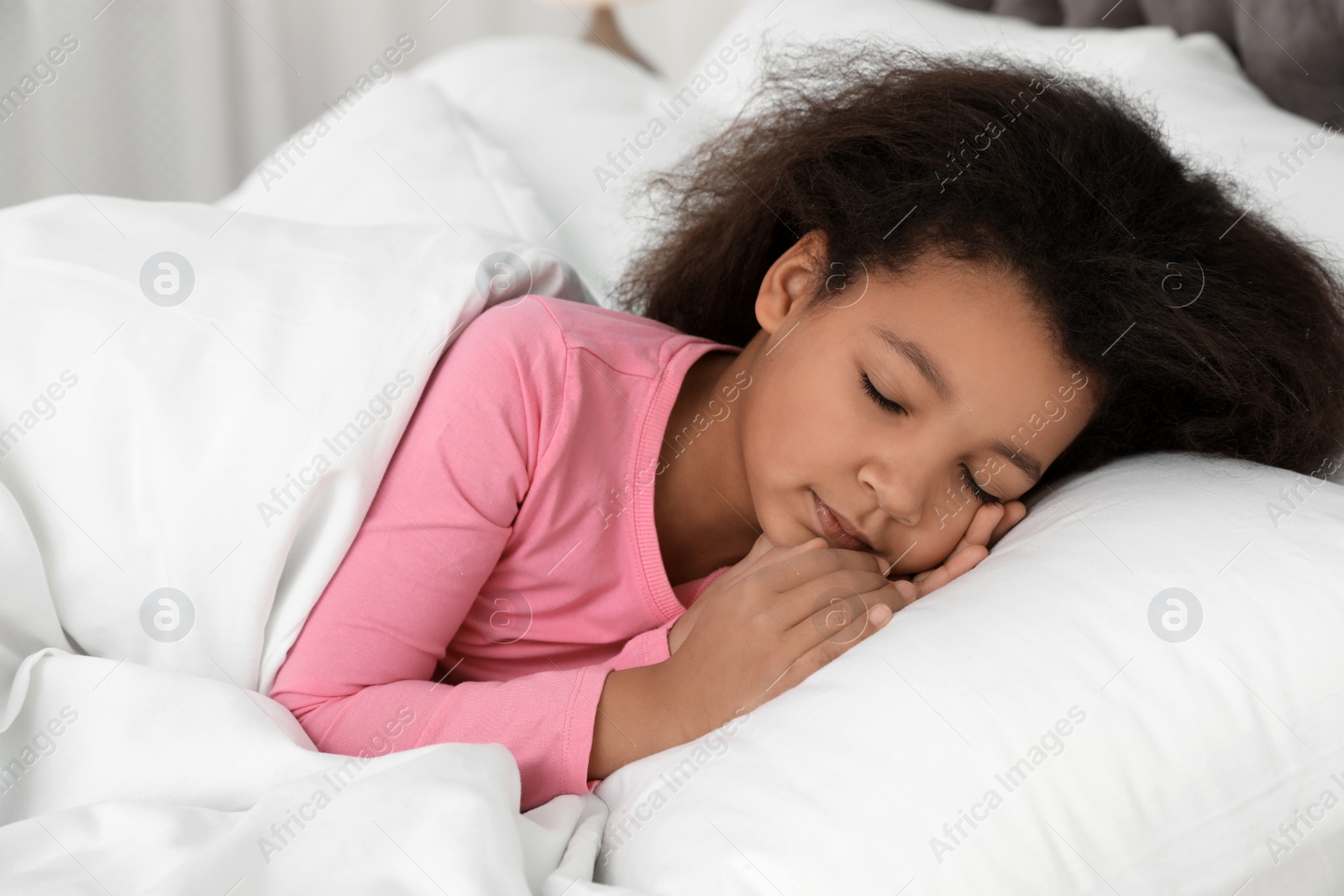 Photo of Cute little African-American girl sleeping in bed