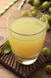 Tasty gooseberry juice and fresh berries on wooden table, closeup