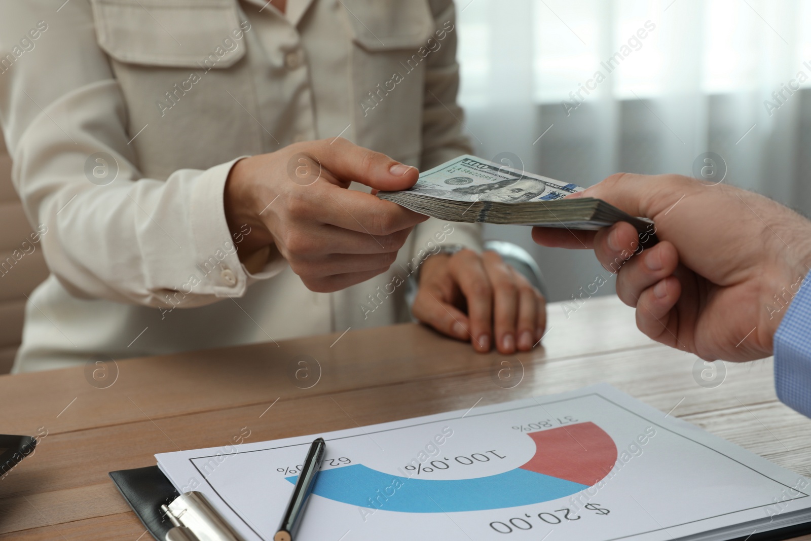 Photo of Cashier giving money to businessman at desk in bank, closeup