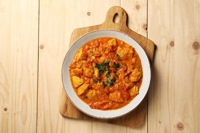 Photo of Delicious chicken curry on wooden table, top view