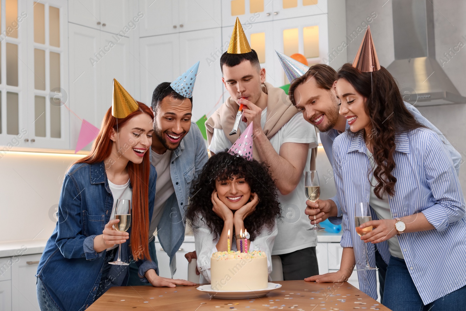 Photo of Happy friends with tasty cake celebrating birthday in kitchen