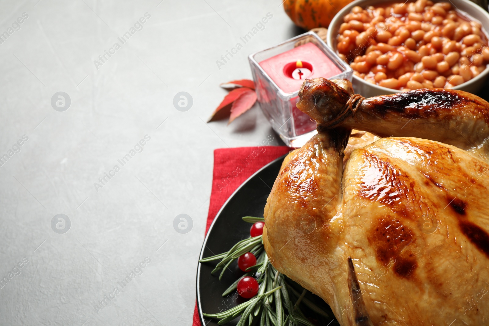 Photo of Traditional Thanksgiving day feast with delicious cooked turkey and other seasonal dishes served on grey table, closeup. Space for text