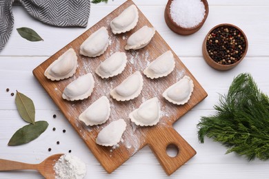 Raw dumplings (varenyky) and ingredients on white wooden table, flat lay