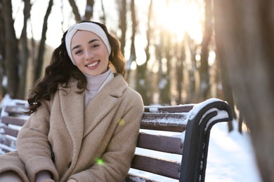 Portrait of smiling woman in sunny snowy park. Space for text