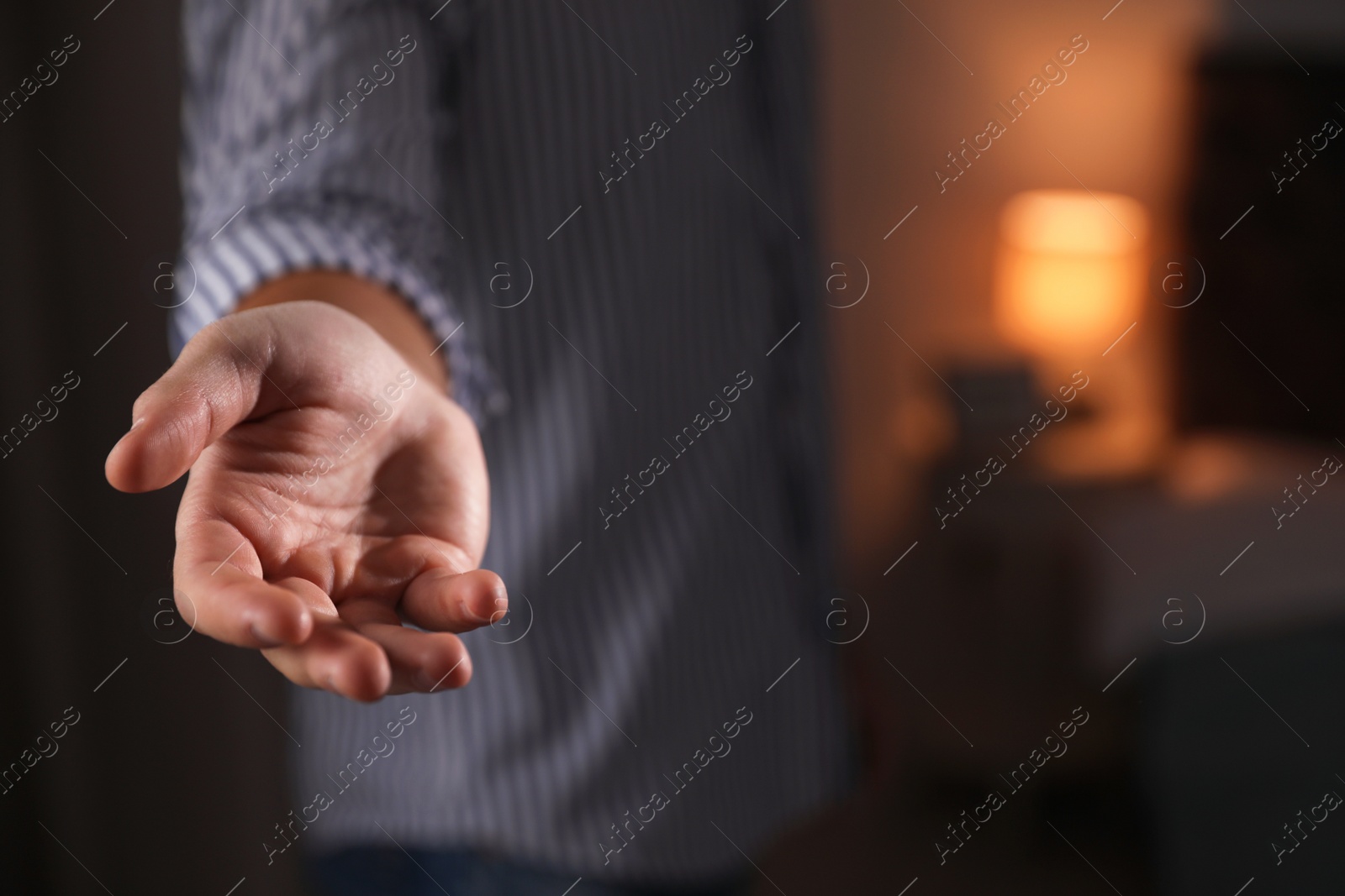 Photo of Man offering helping hand on blurred background, closeup. Space for text