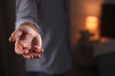 Man offering helping hand on blurred background, closeup. Space for text