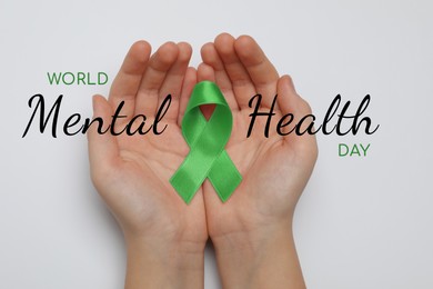Image of World Mental Health Day. Woman holding green ribbon on white background, top view