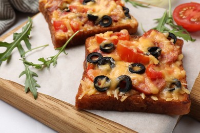 Photo of Tasty pizza toasts and ingredients on white table, closeup