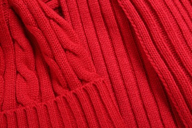 Red knitted scarf and hat as background, top view