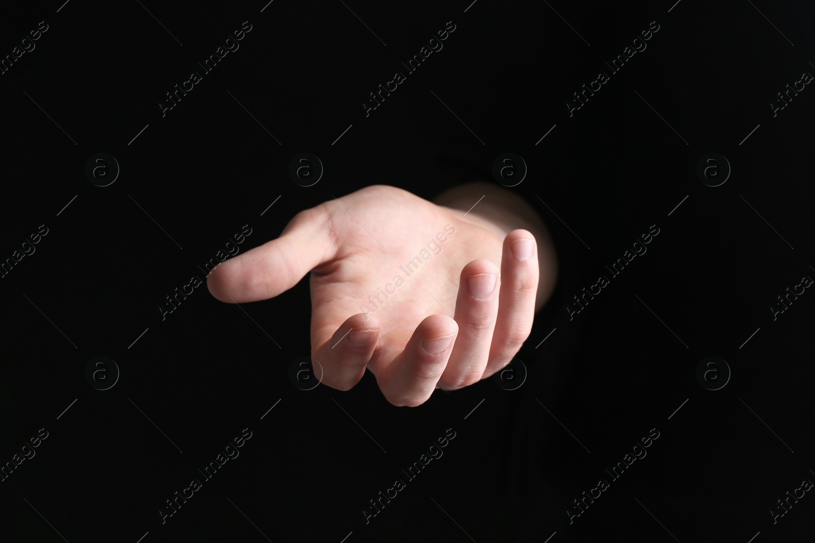 Photo of Man holding something in his hand on black background, closeup