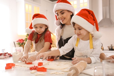 Mother and her cute little children making Christmas cookies in kitchen