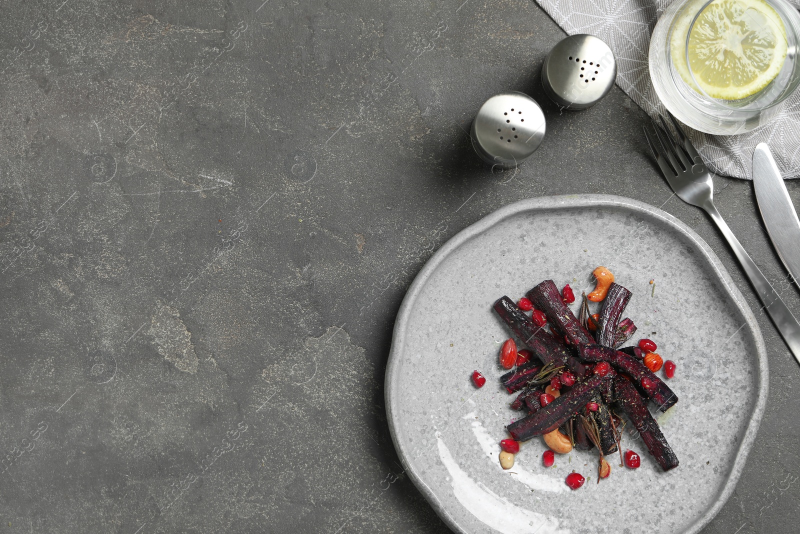 Photo of Tasty baked black carrot served on grey table, flat lay. Space for text