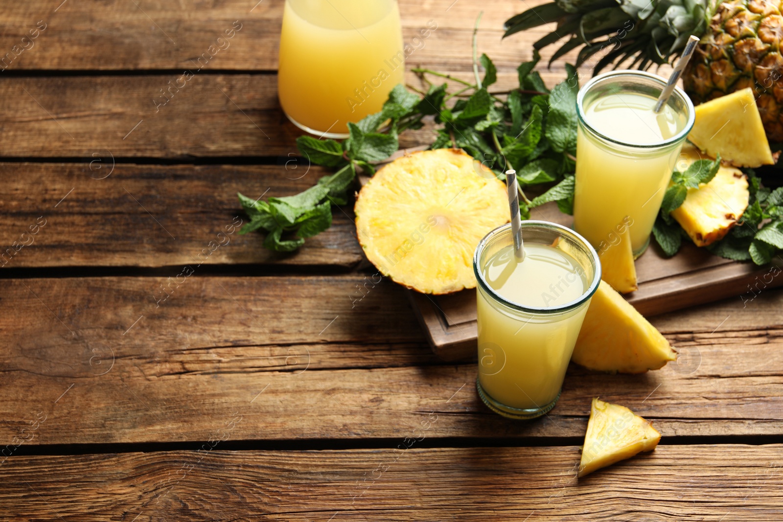 Photo of Delicious pineapple juice and fresh fruit on wooden table. Space for text