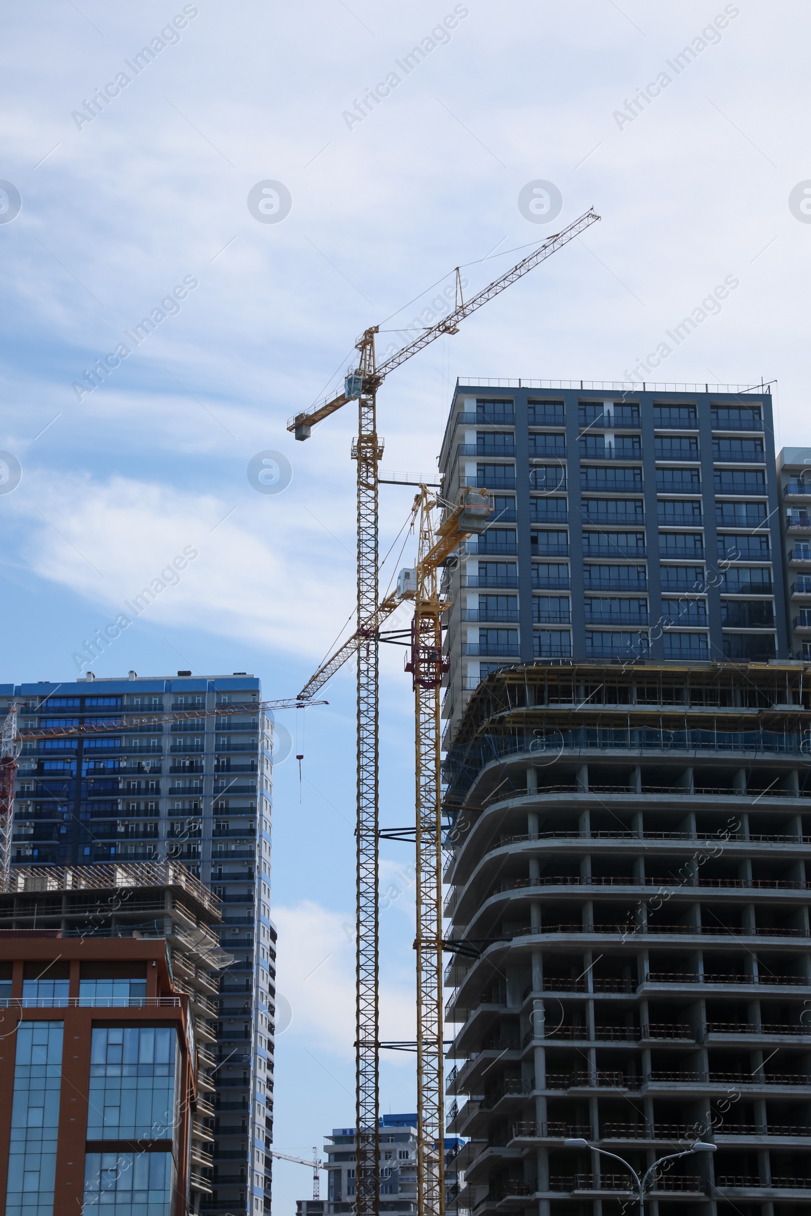 Photo of Construction site with tower cranes near unfinished building, low angle view