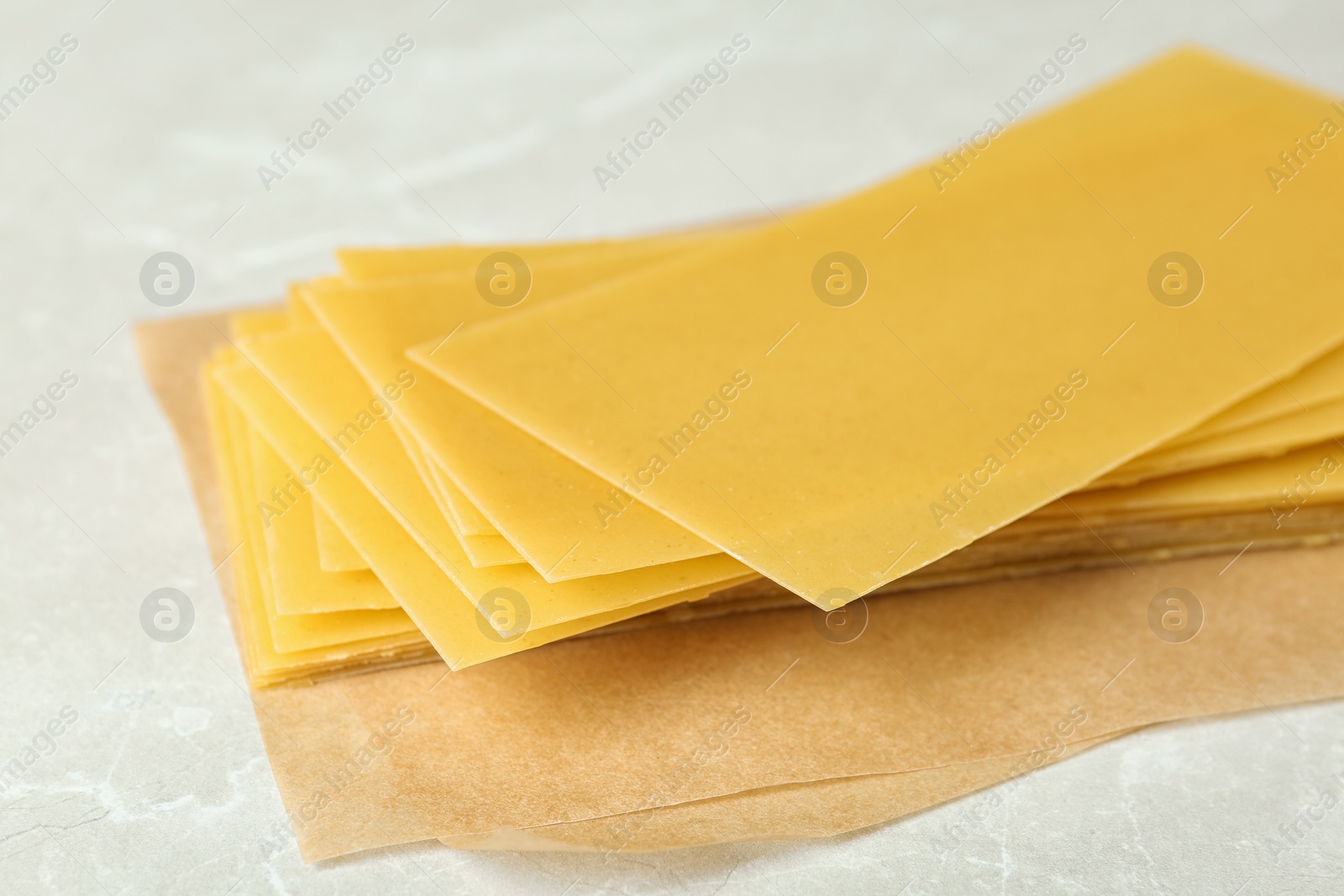 Photo of Uncooked lasagna sheets on marble table, closeup