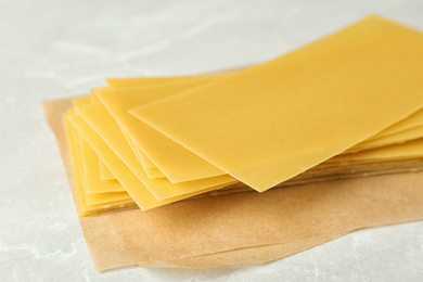 Photo of Uncooked lasagna sheets on marble table, closeup