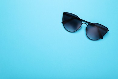 Photo of Stylish sunglasses on light blue background, top view. Space for text