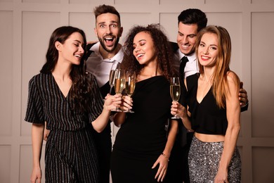 Photo of Happy friends with glasses of sparkling wine celebrating New Year indoors