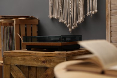 Stylish turntable on wooden crate in room