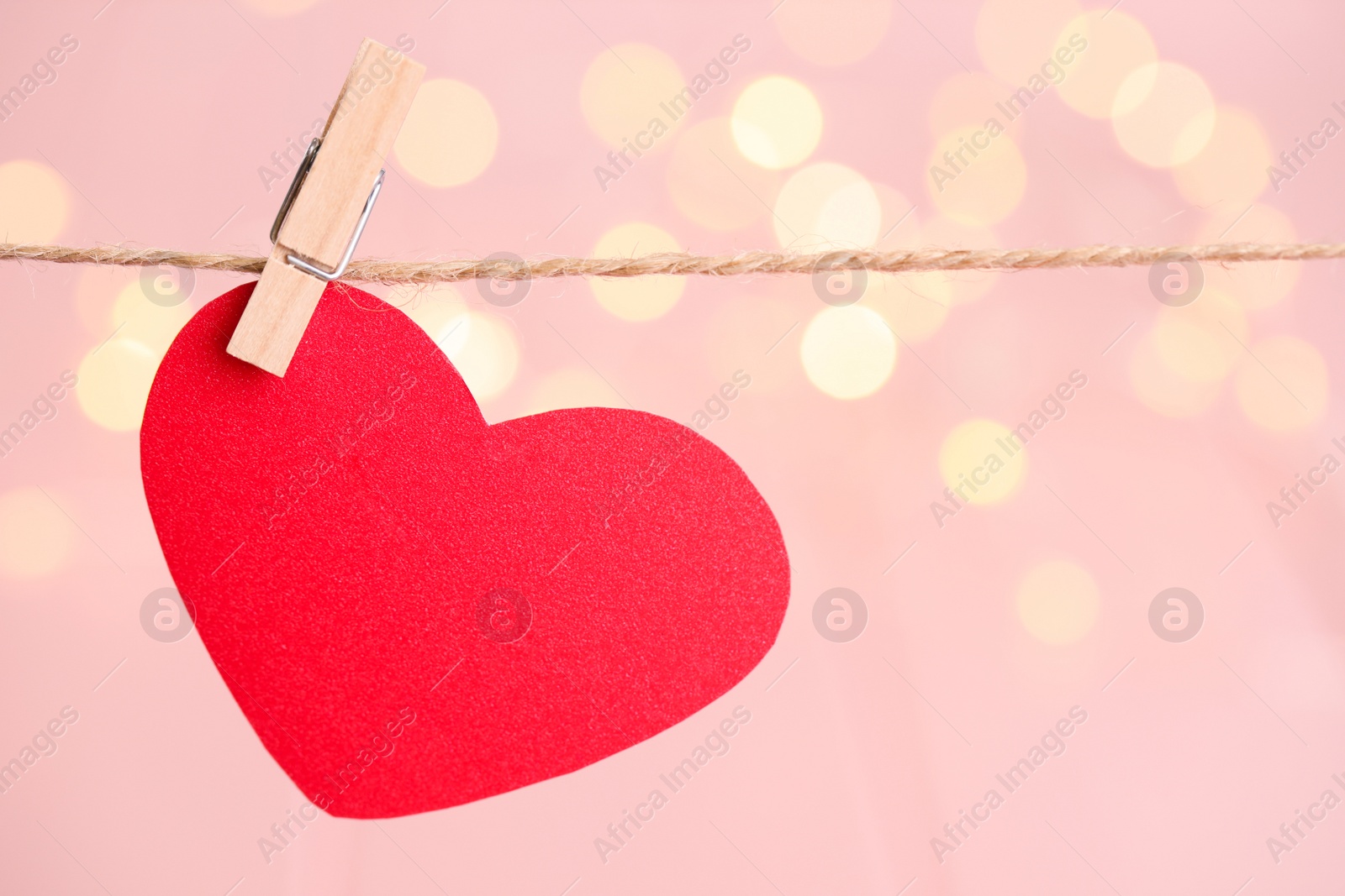 Photo of Red heart hanging on rope against festive lights, space for text. St. Valentine's day