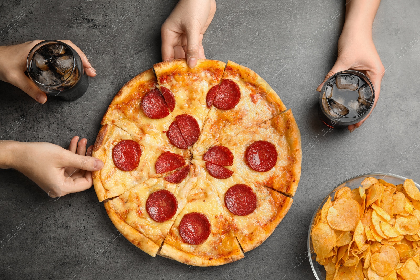 Photo of Women taking tasty pepperoni pizza at grey table, top view