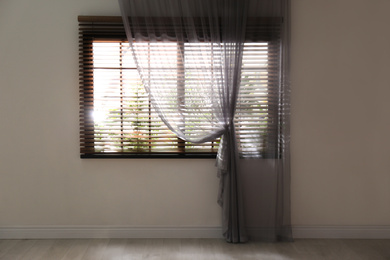 Photo of Window with beautiful curtain and blinds in empty room