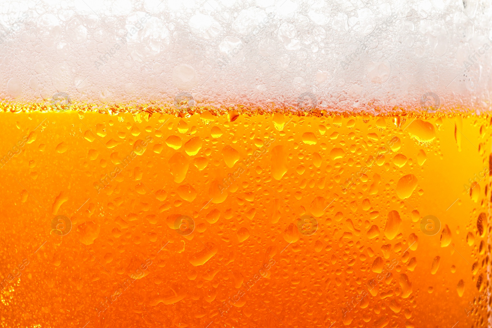 Photo of Glass of tasty cold beer with foam and condensation drops as background, closeup