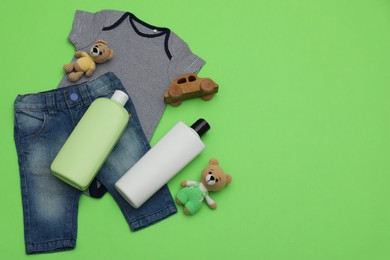 Photo of Bottles of laundry detergents, baby clothes and toys on light green background, flat lay. Space for text